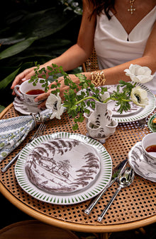 Woman in a white top sits at an outdoor table sipping tea from a Country Estate Flint Teacup.